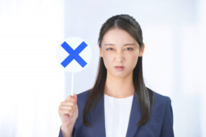 カメラ目線の女性-バツマークを上げる
