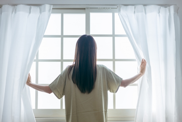 カーテンを開ける女性