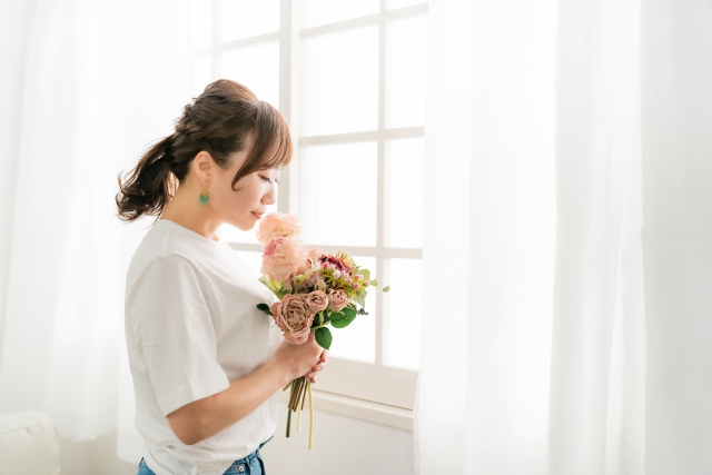 花の香りを嗅ぐ女性